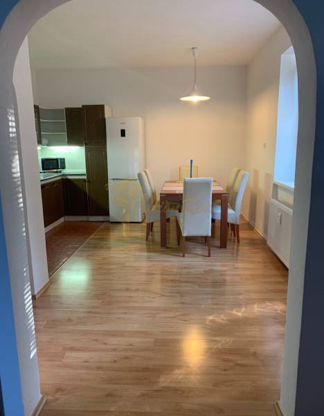 Dining area in a 2-room apartment with a wooden decor floor and four chairs.
