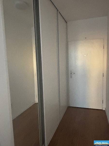 A hallway in a 2-room apartment with a large wardrobe and a floor with a wooden decor.