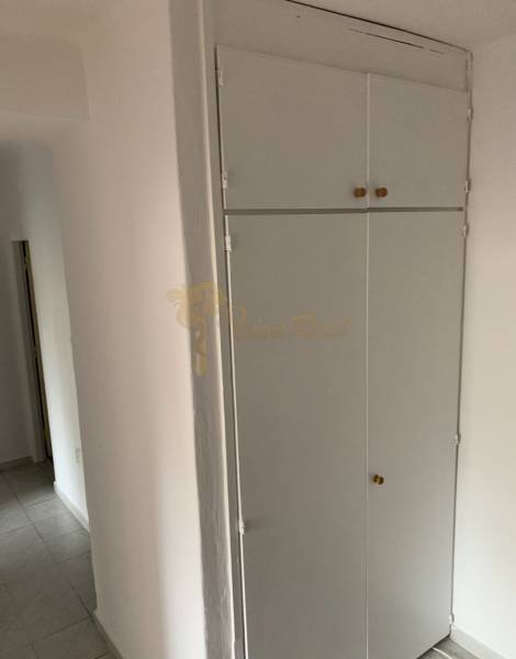 White built-in wardrobe in the hallway of a 2-room apartment with tiles.