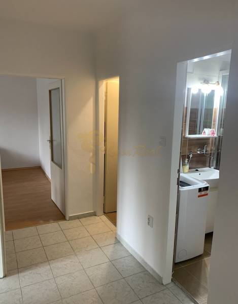 A hallway with entrances to the bathroom and a room in a 2-room apartment, tiled floor.