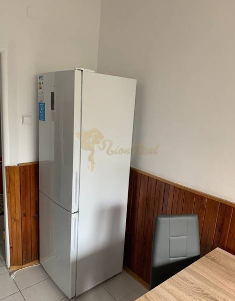 A kitchen in a 2-room apartment with a refrigerator, dark tiles, and a dining area.