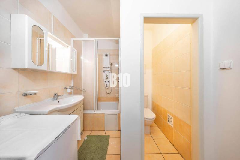 A bathroom in a 4-room apartment with a bathtub, cabinets, and a toilet, decorated in light colors.