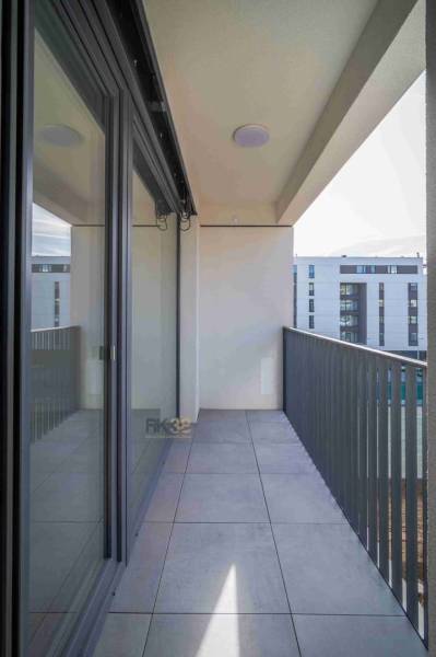 Balcony of a 2-room apartment in Poprad with tiles and a view of modern buildings.