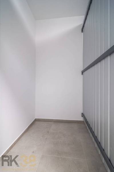Storage space with tiled flooring in a 2-room apartment with smooth white walls.