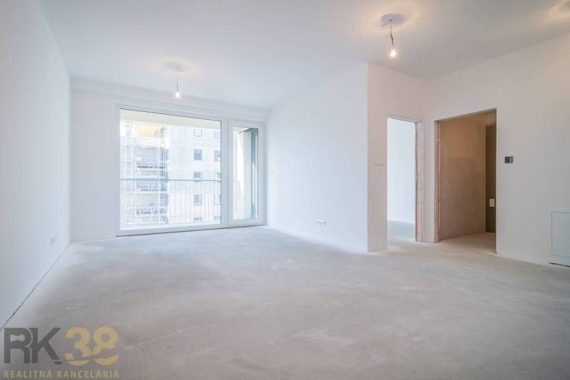 Spacious living area in a 2-room apartment with large windows without flooring with wooden decor.