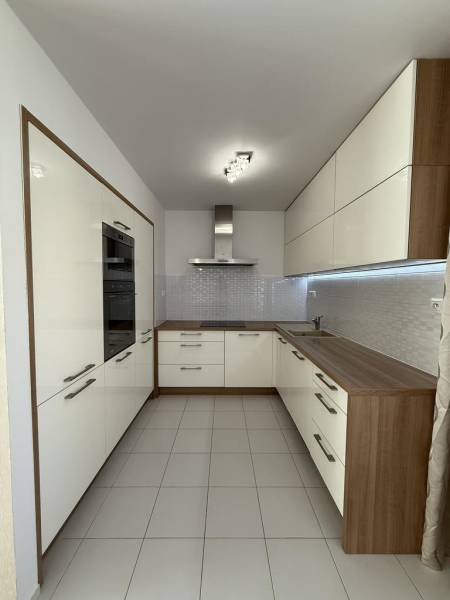 A kitchen in a 4-room apartment with light cabinets and tiled flooring.
