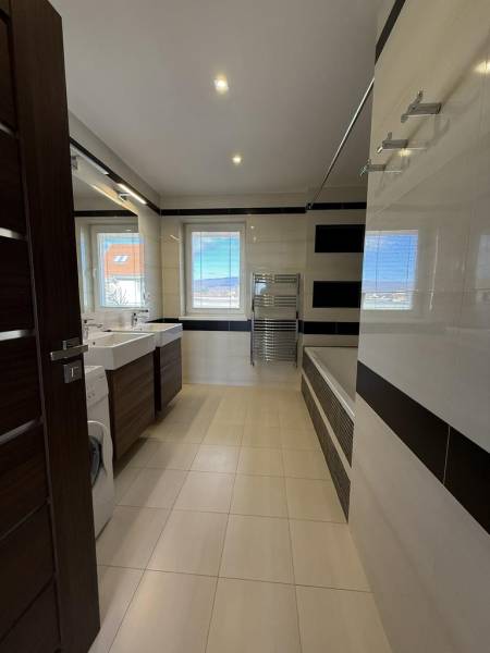 Bathroom in a 4-room apartment with a bathtub, sinks, and a washing machine.
