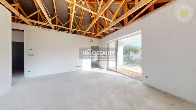 Interior of a family house with an exposed ceiling and large glass doors.