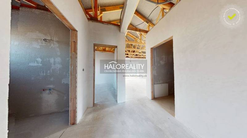 An unfinished interior of a family house with a wooden roof structure and open rooms.