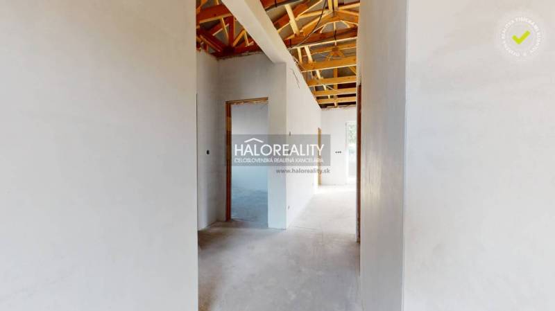 Interior of a family house with a roof structure and white plastered walls.