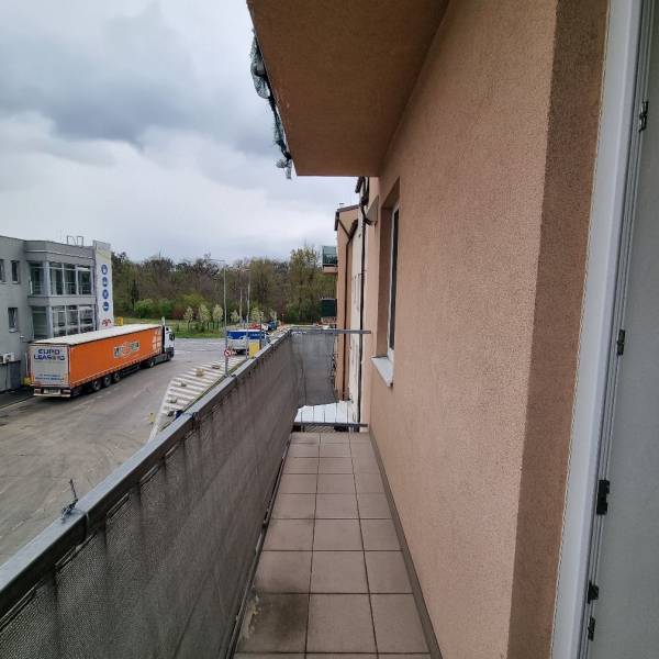 The balcony of a studio apartment on Pezinská Street in Malacky with a view of the parking lot and greenery.