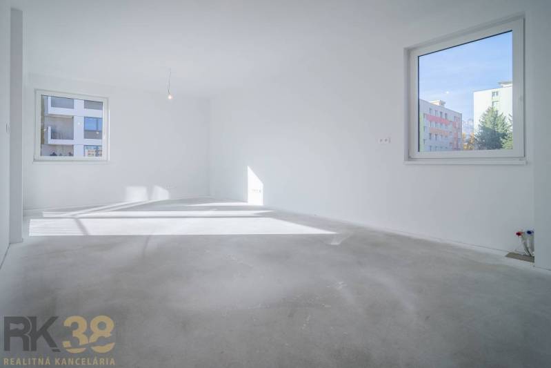 An empty room in a three-room apartment with light walls and large windows, without flooring with a wooden decor.