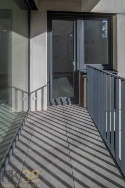 A balcony with tiles and glass railing in a 3-room apartment.