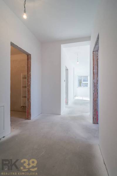 A hallway in a 3-room apartment with a large window and unfinished doors.
