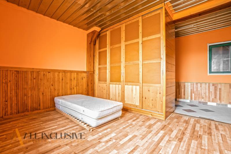 Interior of a family house with a wooden decor floor, a mattress, and a built-in wardrobe.