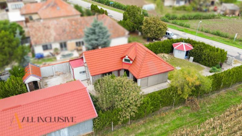 A family house in Bátorove Kosihy, red roof, green surroundings, adjacent buildings.