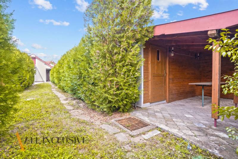 A garden shelter behind a family house in Bátorove Kosihy, surrounded by coniferous trees.