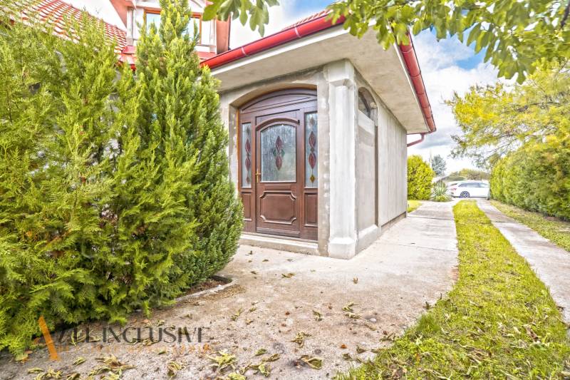A family house in Bátorove Kosihy with glazed doors and ornamental conifers.
