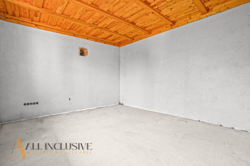 Unfurnished room in a family house with a wooden ceiling and white walls.