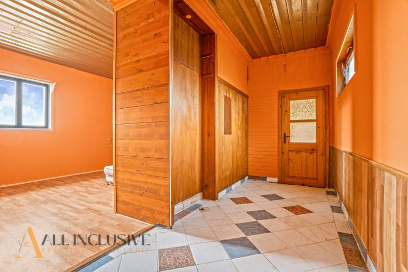 A hallway in a family house with tiles and orange walls, complemented by wooden elements.