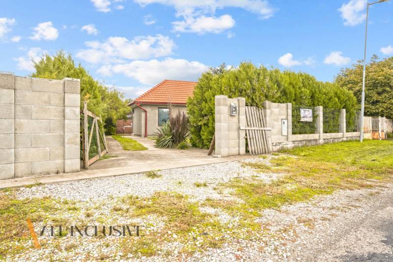 A family house in Bátorove Kosihy, surrounded by greenery, with a path leading to the gate.