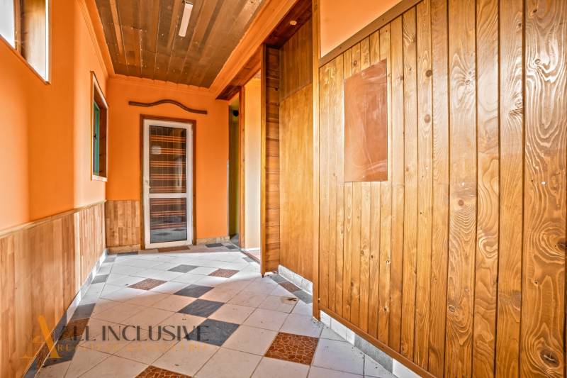 A hallway in a family house with wooden paneling and a tiled floor.