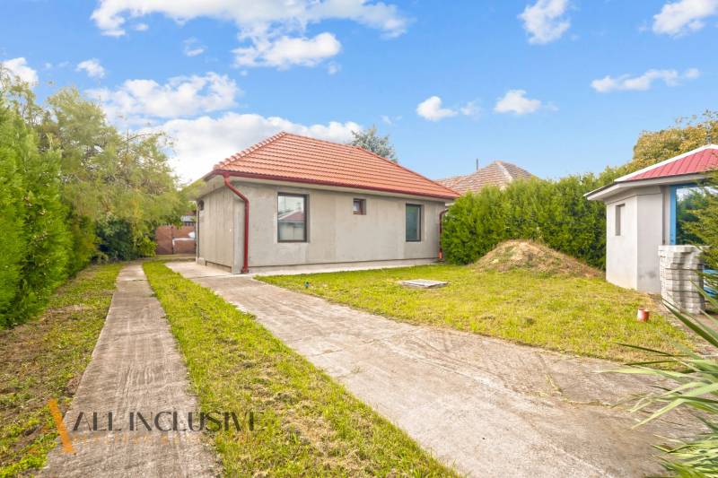 A family house in Bátorove Kosihy, with a lawn, concrete walkway, and a red roof.