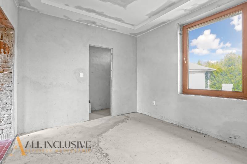 Interior of a family house with unfinished walls and a large window.
