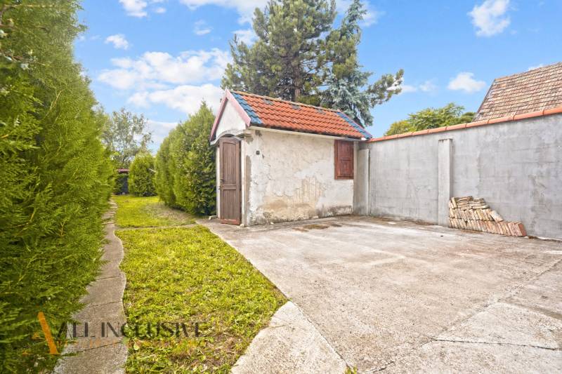 The garden of a family house in Bátorove Kosihy with a path and a gazebo lined with a hedge.