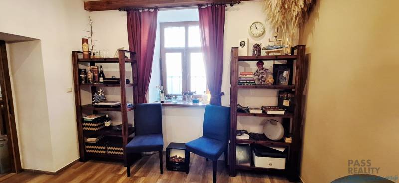 Bookshelves with decorations, chairs, and a window with burgundy curtains in a commercial space.