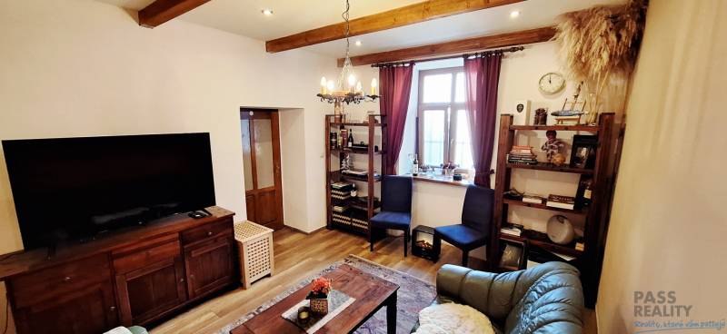Living room with wood-patterned flooring, a television, shelves, and comfortable furniture.