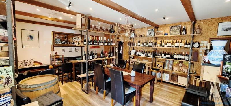 Interior of commercial premises with wood-decor flooring, full of wine bottles and wooden elements.