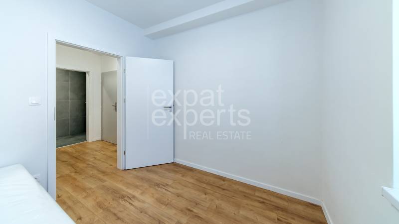 A room in a 3-room apartment with a wooden decor floor and white walls.