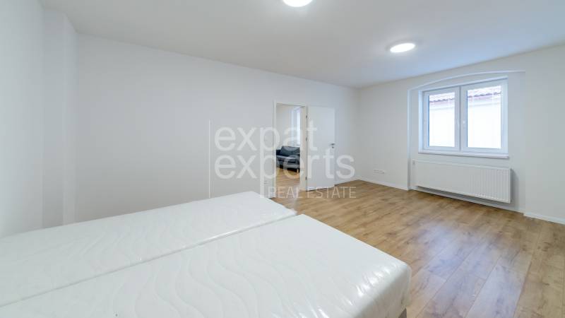 Bedroom in a 3-room apartment with wood-patterned flooring and white walls.