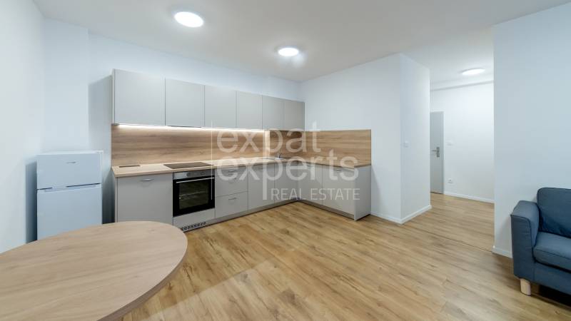 A kitchen in a 3-room apartment with a wooden decor floor and light furniture.