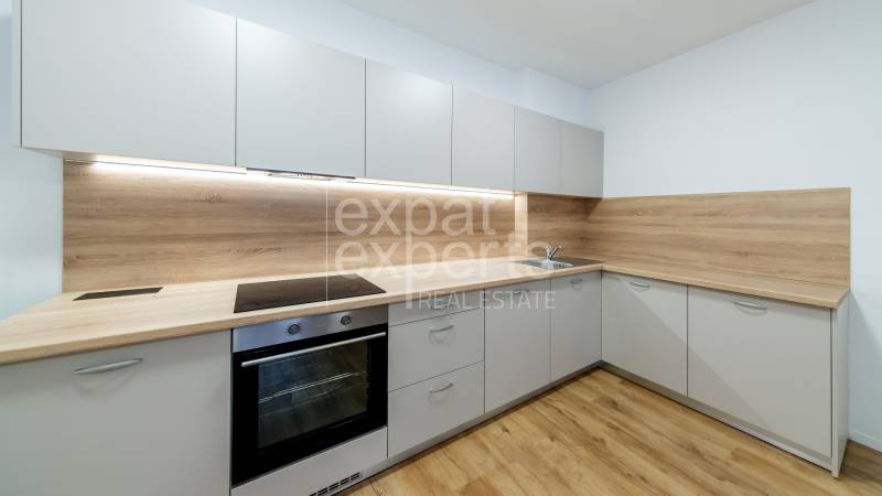 A kitchen in a 3-room apartment with a wood-patterned floor and built-in appliances.