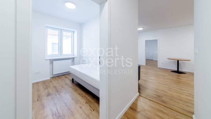 Bright 3-room apartment with a bed and wooden decor flooring.