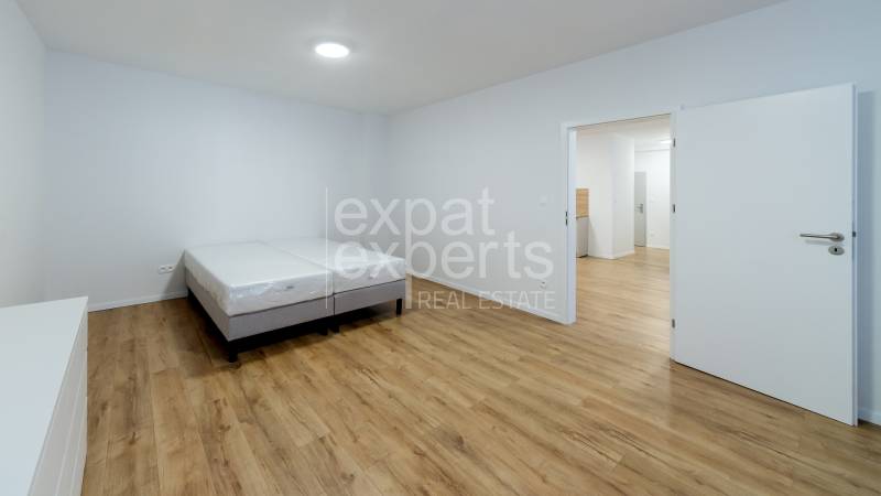 Bedroom in a 3-room apartment with a bed and a wooden decor floor.