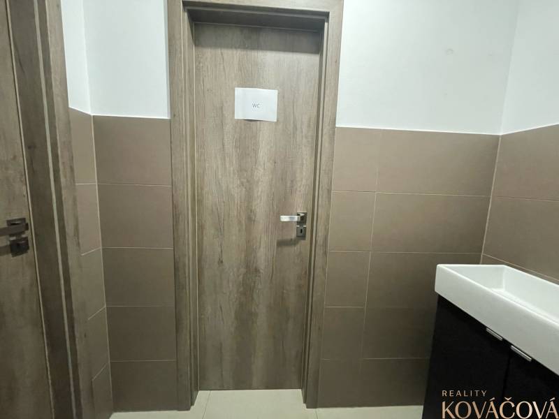 Interior of commercial premises with WC doors, paneled walls, ceramic sink.