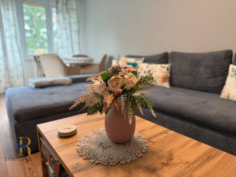 A comfortable living room in a two-room apartment with a sofa and flowers on the table.