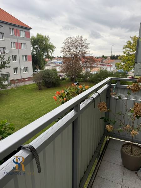The balcony of the green 2-room apartment in Sereď with a view of greenery and the neighboring house.