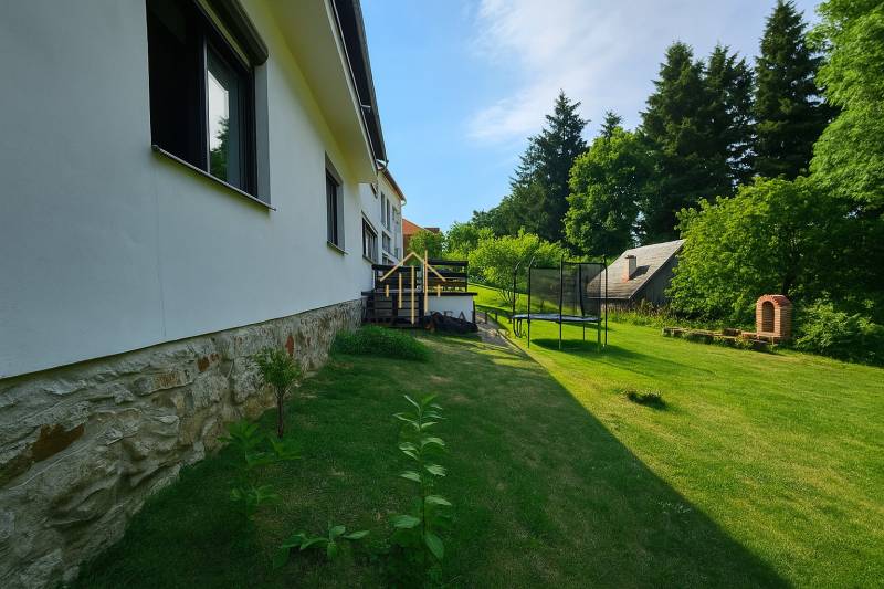 A family house on Hájik Street in Banská Štiavnica with a lawn and a trampoline in the garden.