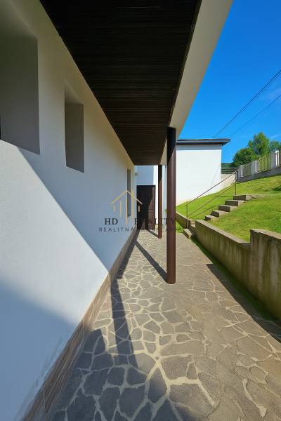 A walkway to a family house in Banská Štiavnica, Hájik, bordered by a grassy slope.