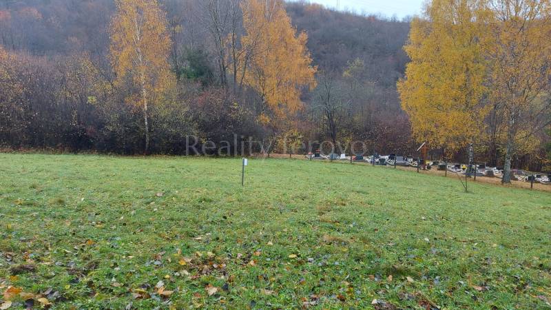 Grassy recreational plots in Jeseni in Podhradie, Konské, with colorful deciduous trees in the background.