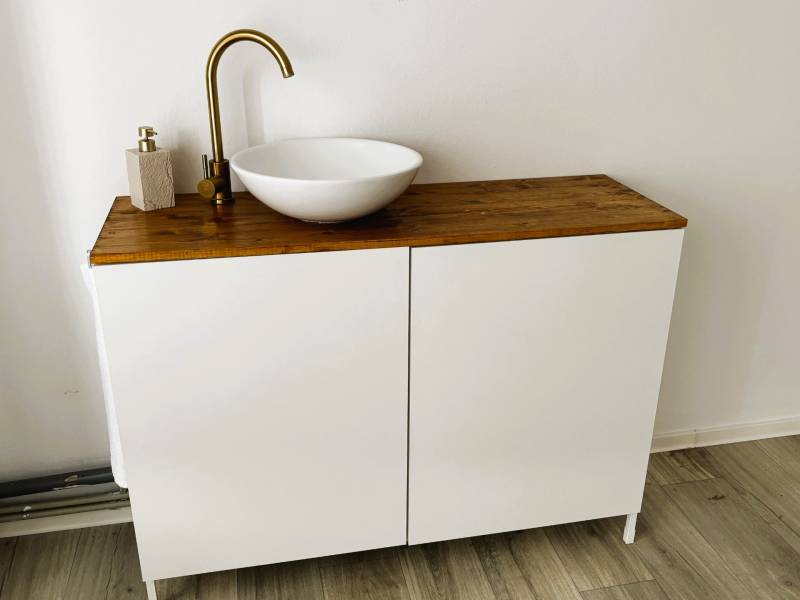 Sink on a wood-decor countertop, white cabinet, and floors with wood decor.