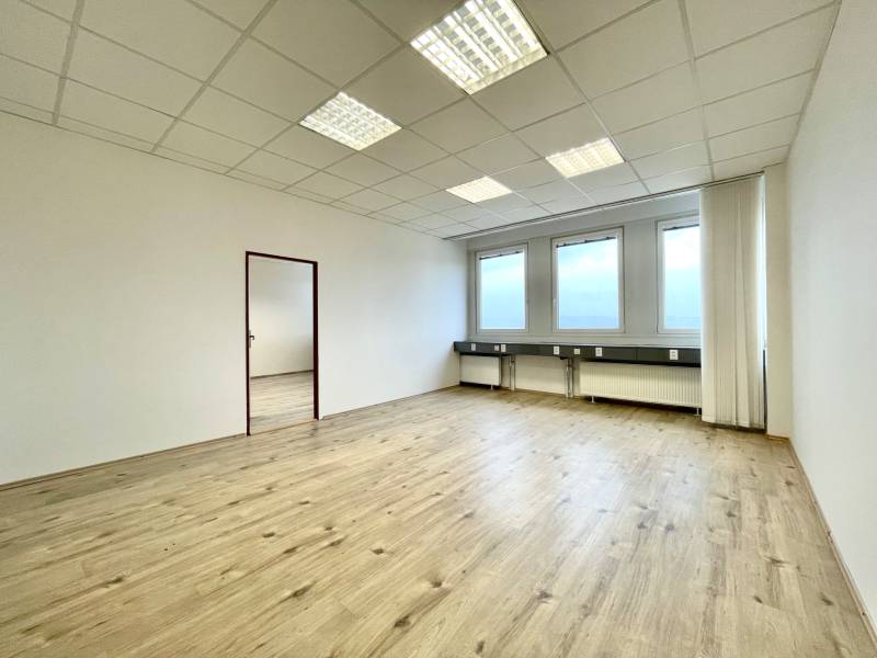 An office with a wood-decor floor and large windows, neutral colors.