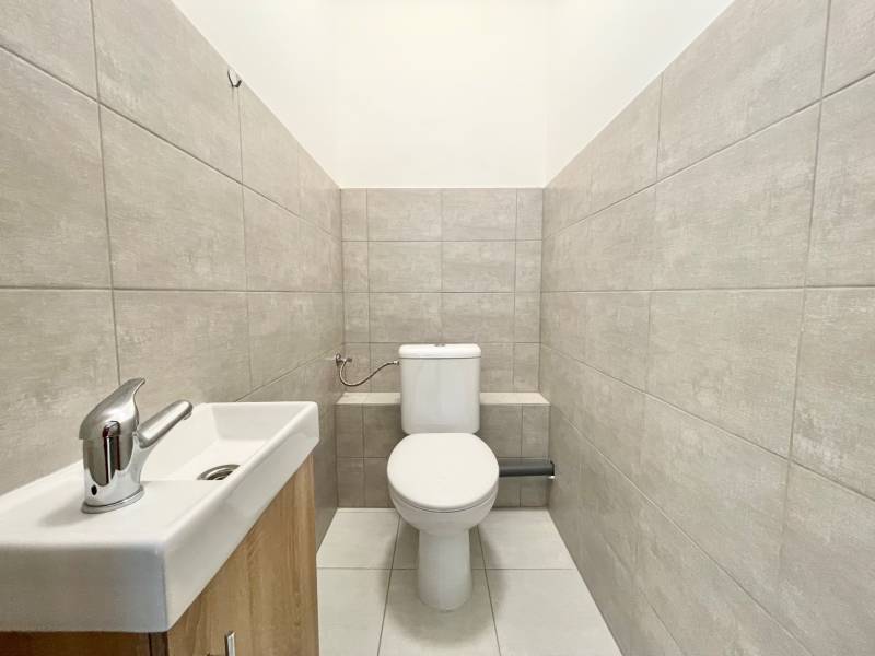 A restroom with gray tiles and a sink in the office.
