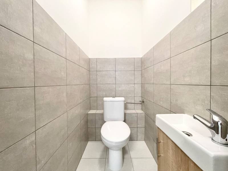 A toilet with a sink and gray tiles in an office interior.