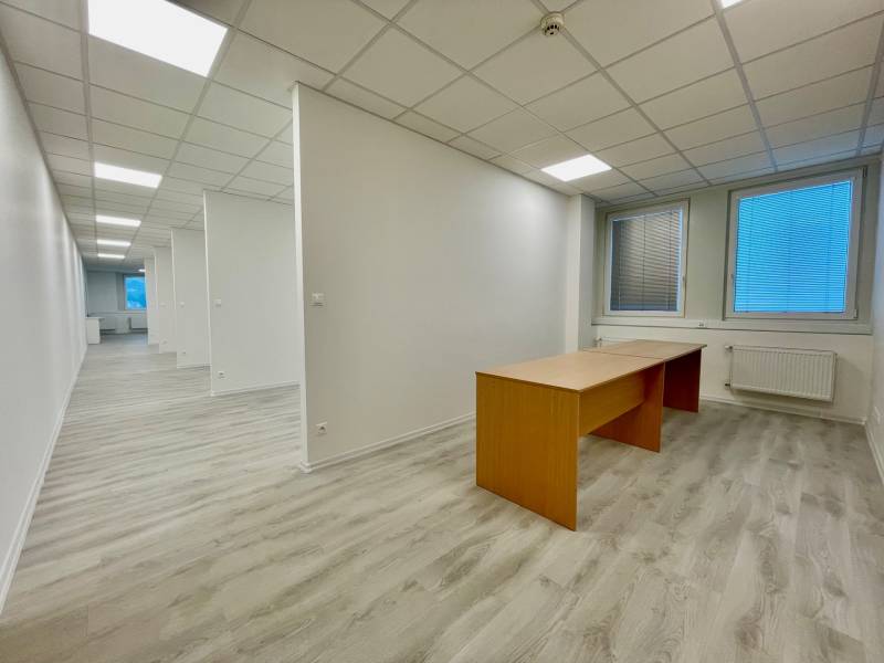 White offices with wood-patterned flooring, minimalist furniture, neutral lighting.