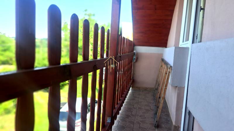 A balcony with a view in a cottage in Hontianske Trsťany. Wooden railing and tiled floor.